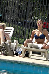 A hot bikini chick sitting at the swimming pool